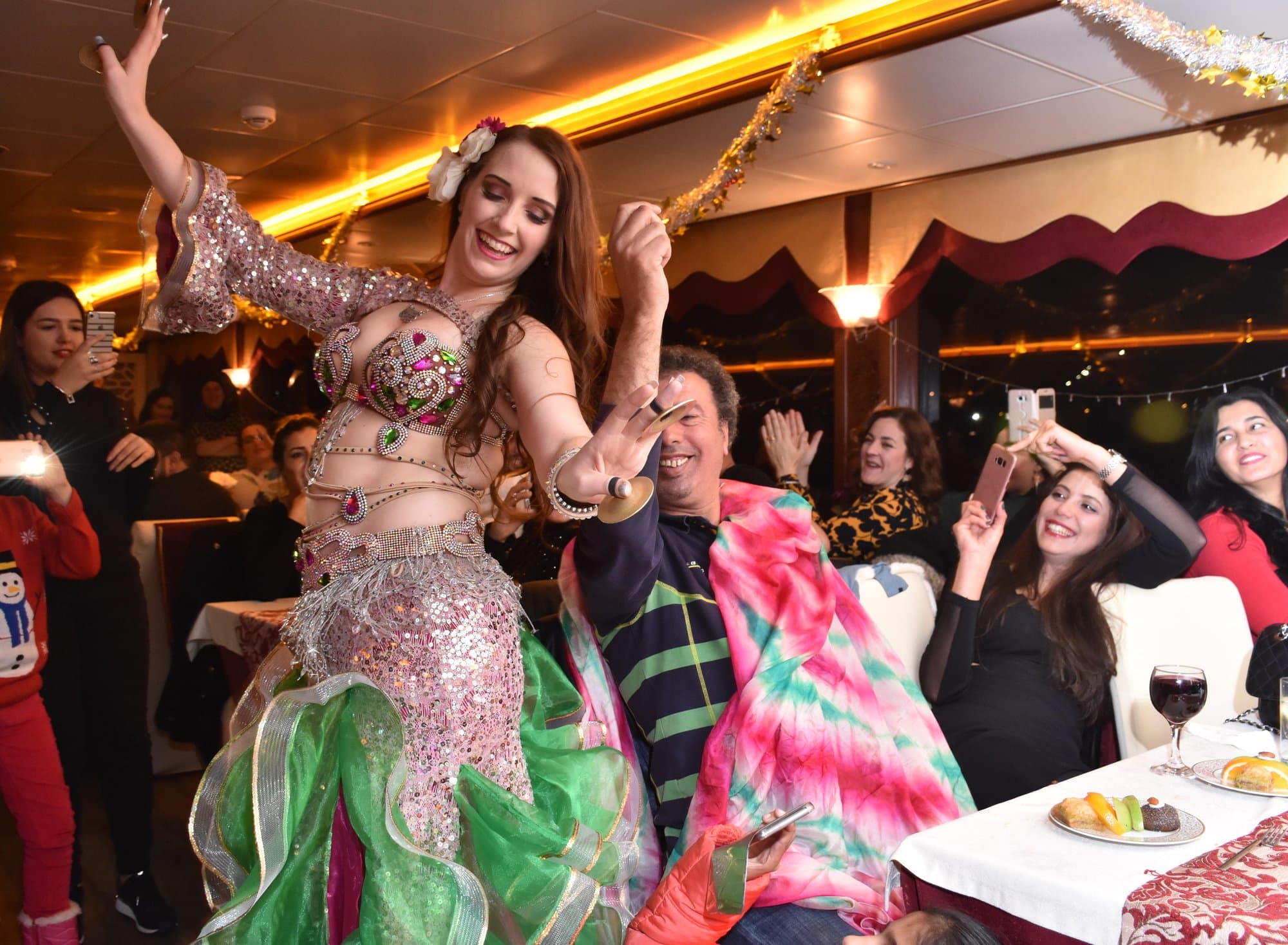 A belly dancer performing beside guests at their table on the dinner cruise