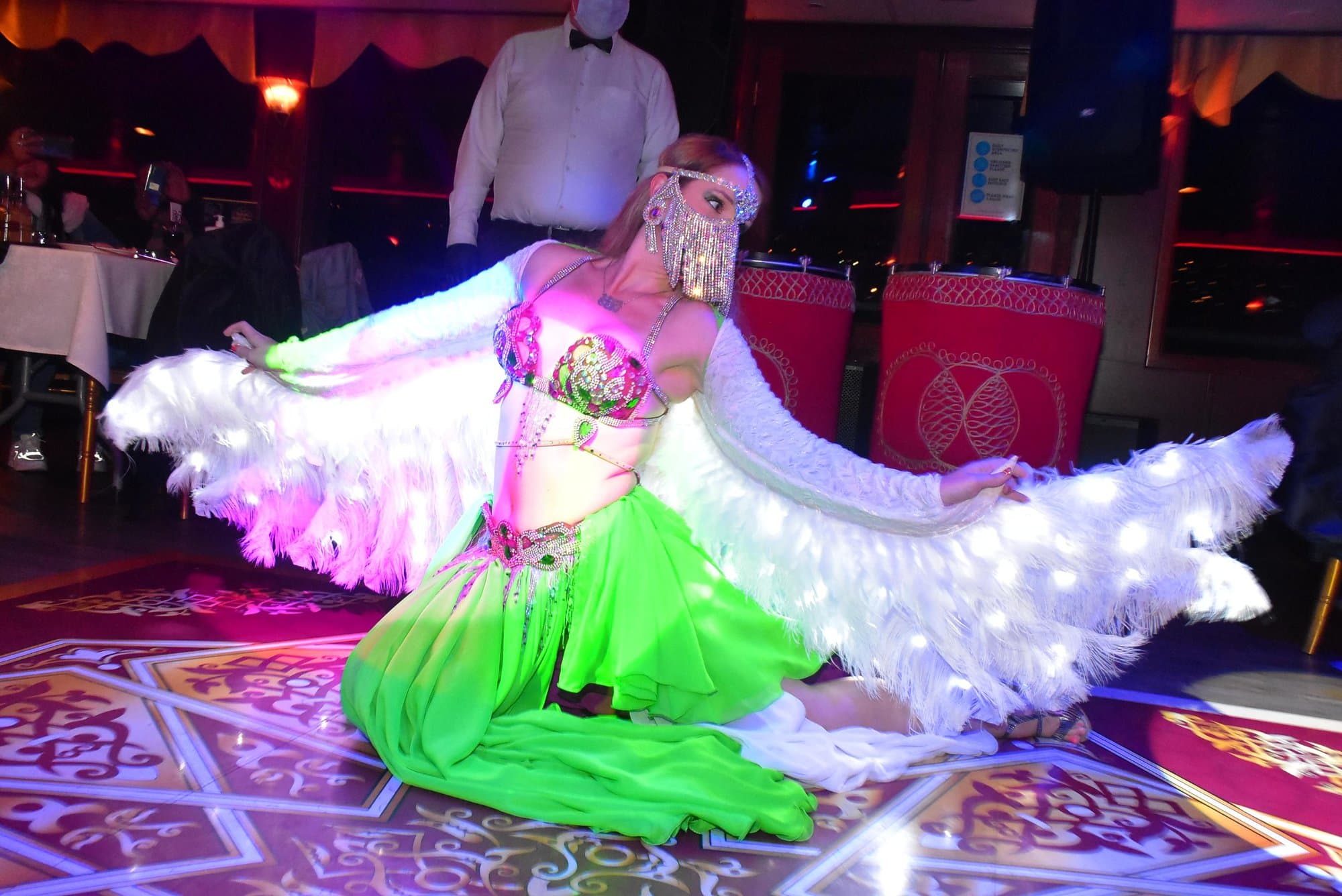 A belly dancer with illuminated feather wings performing on the cruise