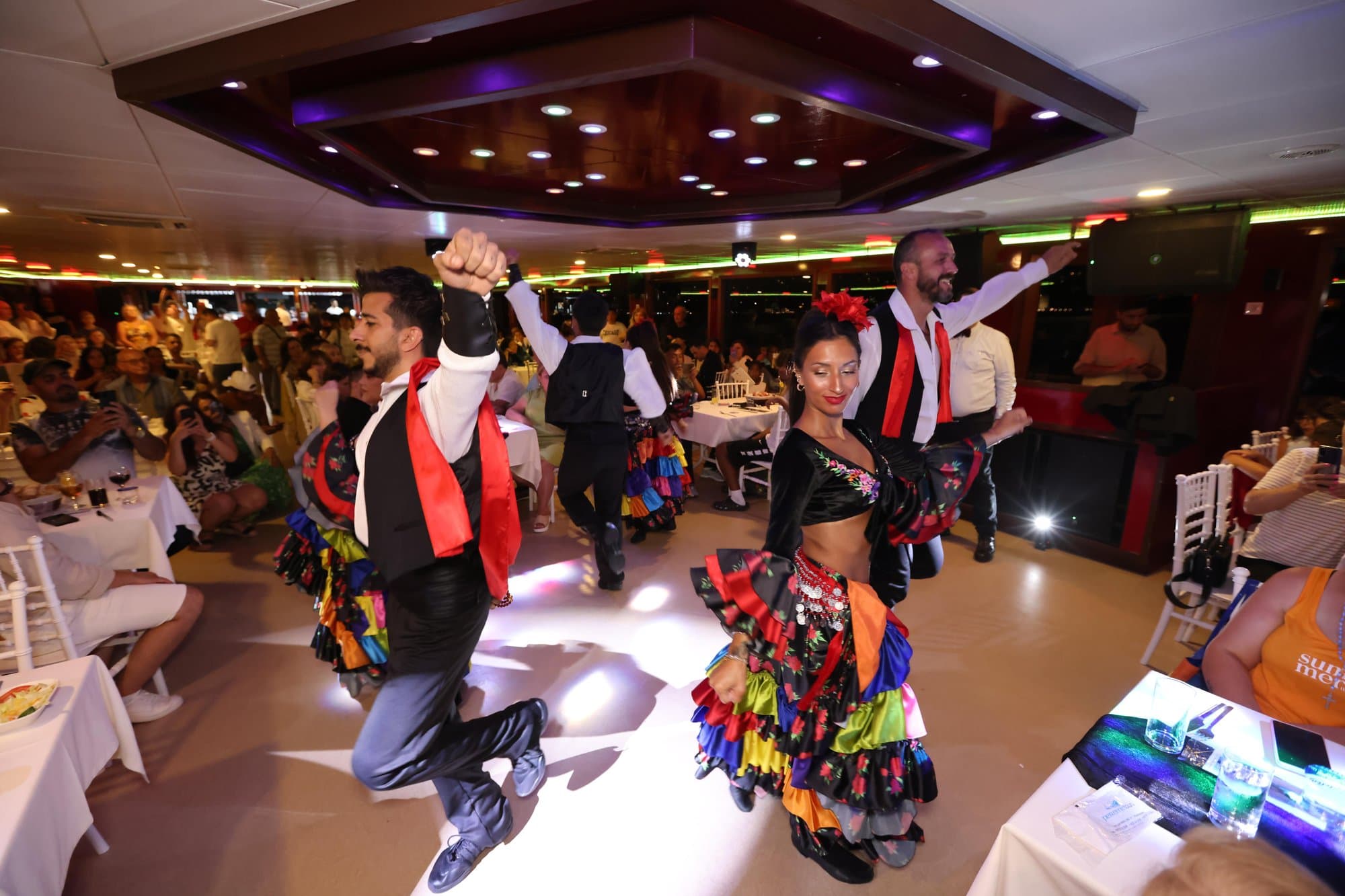 Folk dancers in colourful costumes performing among the diners on the cruise