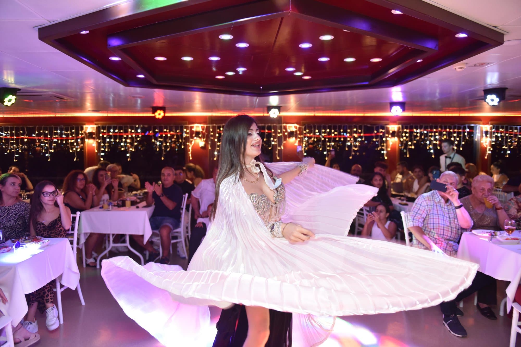 A dancer spinning in a white dress on the dinner cruise dance floor