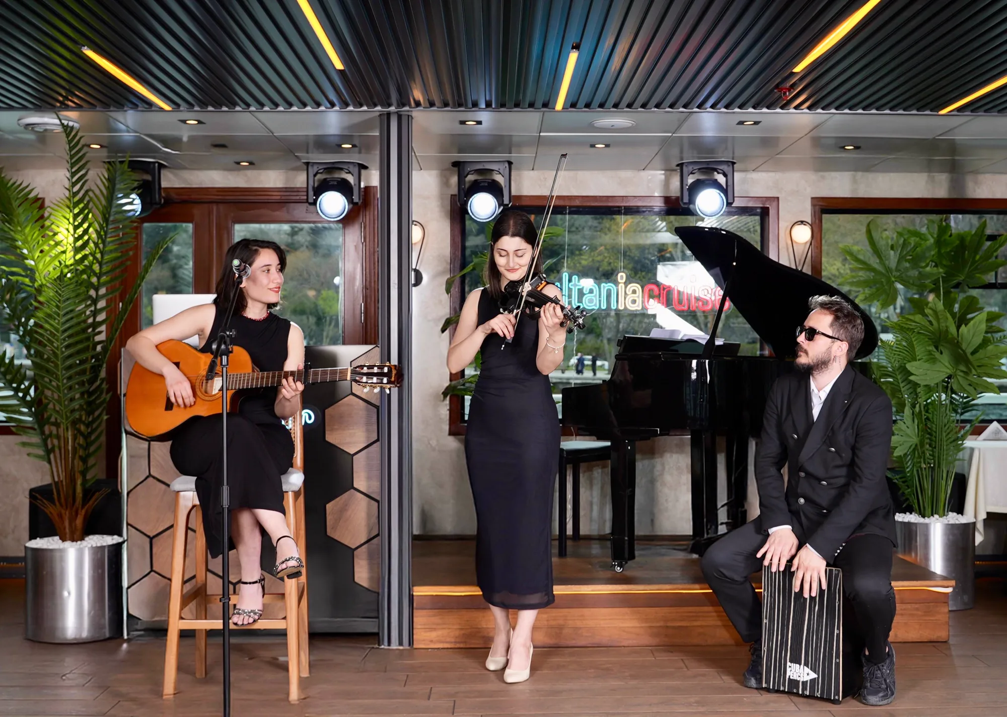 A live music trio with guitar, violin and cajon performing in the boat's lounge