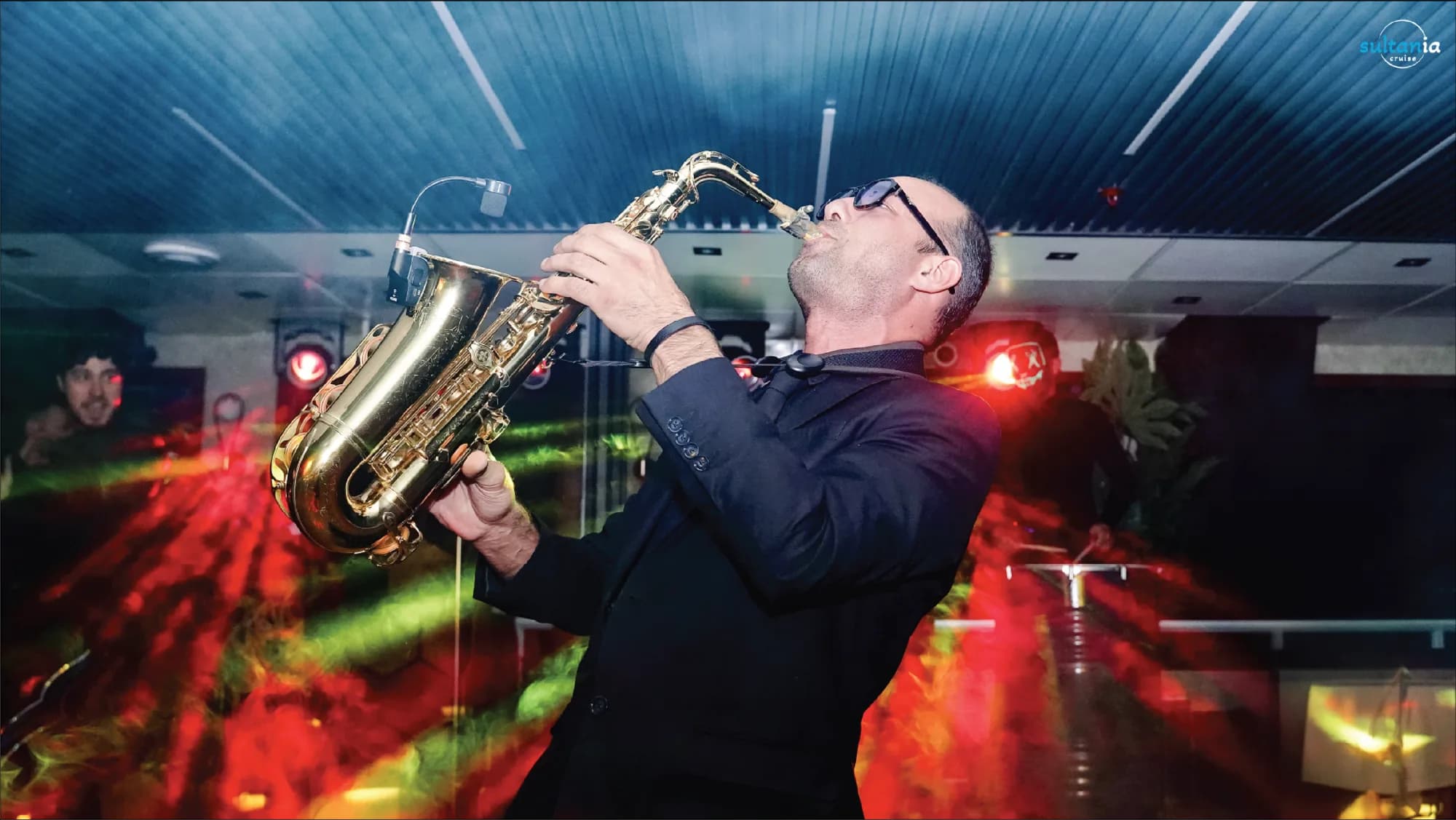 A saxophonist performing under stage lights during the evening cruise