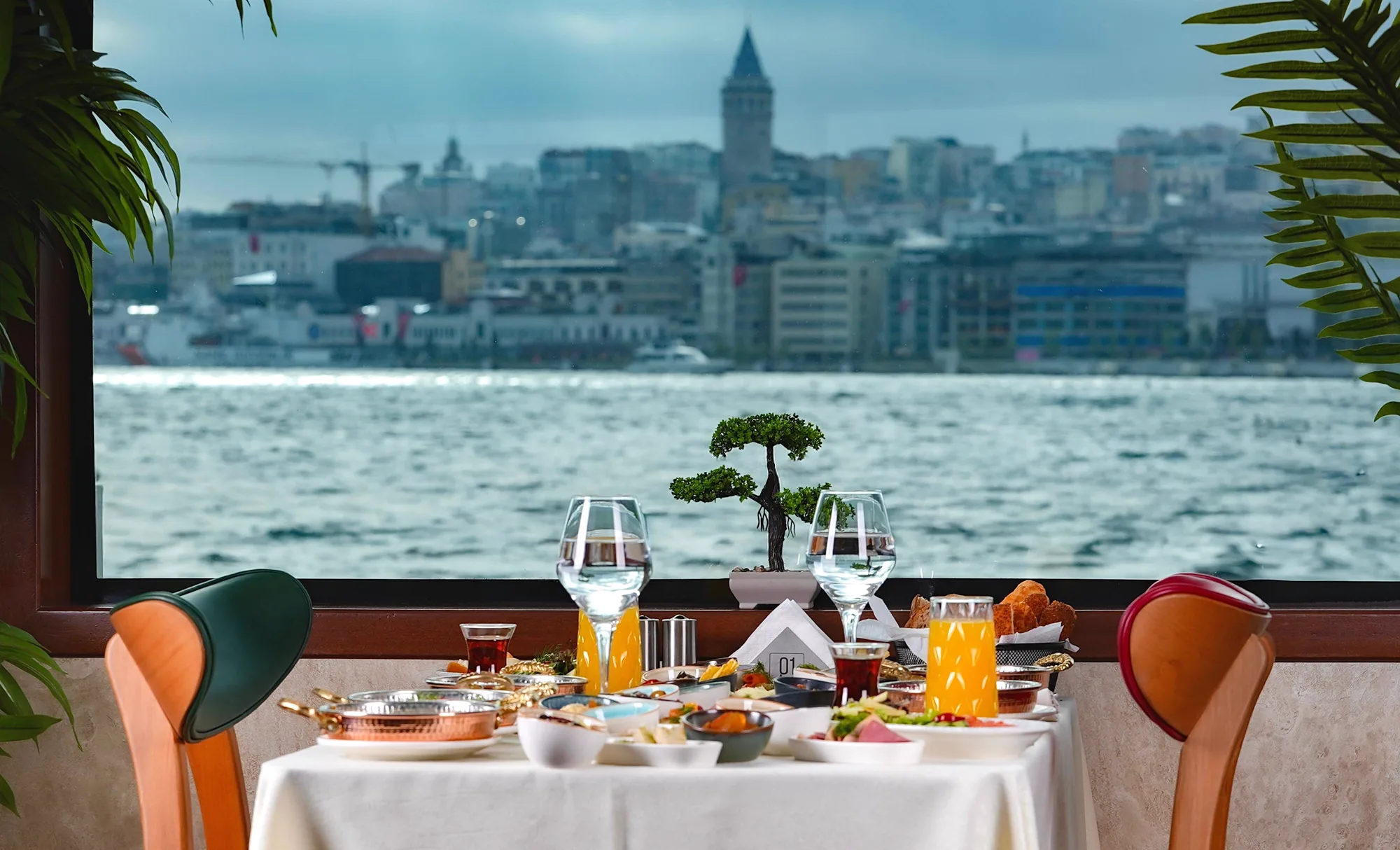 A dinner table by the window on the boat with a view of the Galata Tower