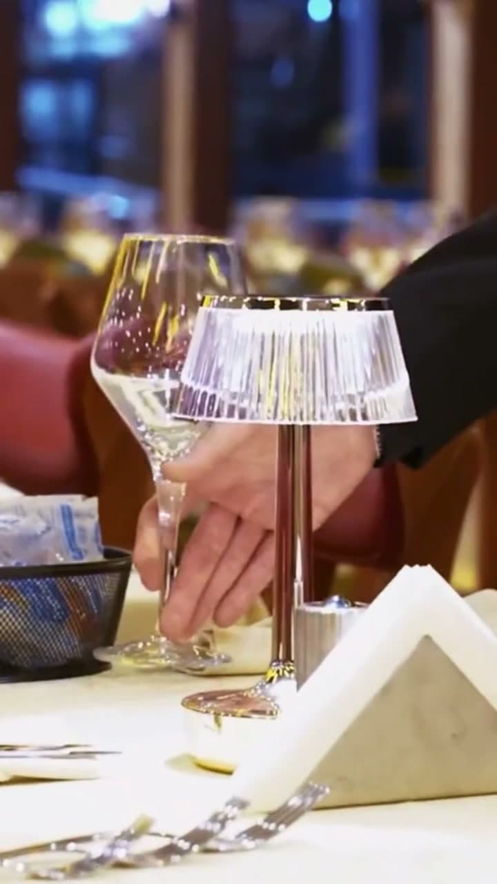 A wine glass and table lamp on a set dinner table in the boat's dining lounge