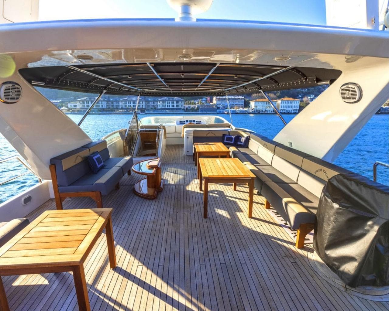 The yacht's covered aft deck with teak tables and sofas overlooking the Bosphorus