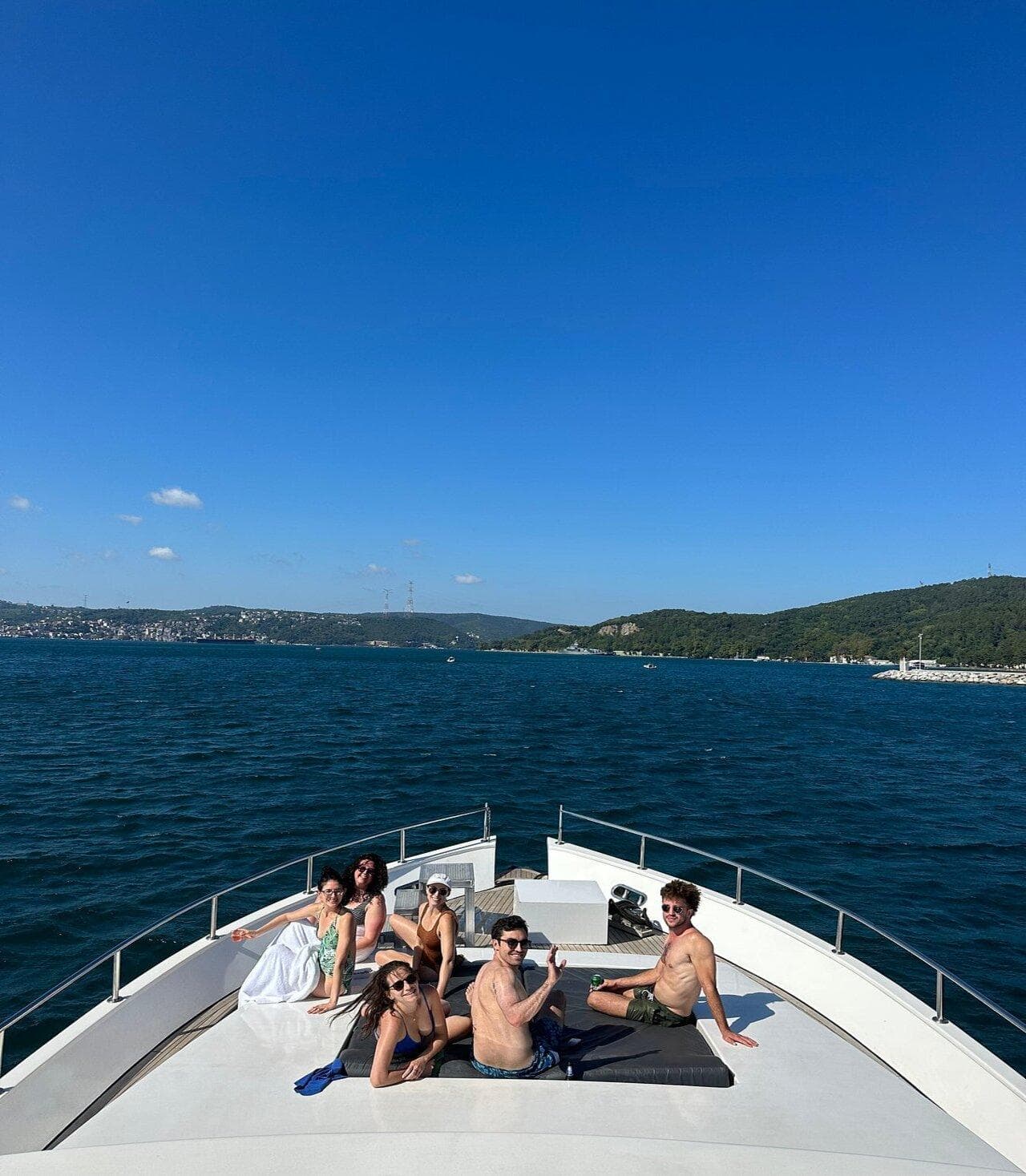 A small group lounging on the private yacht's foredeck on a sunny day on the Bosphorus