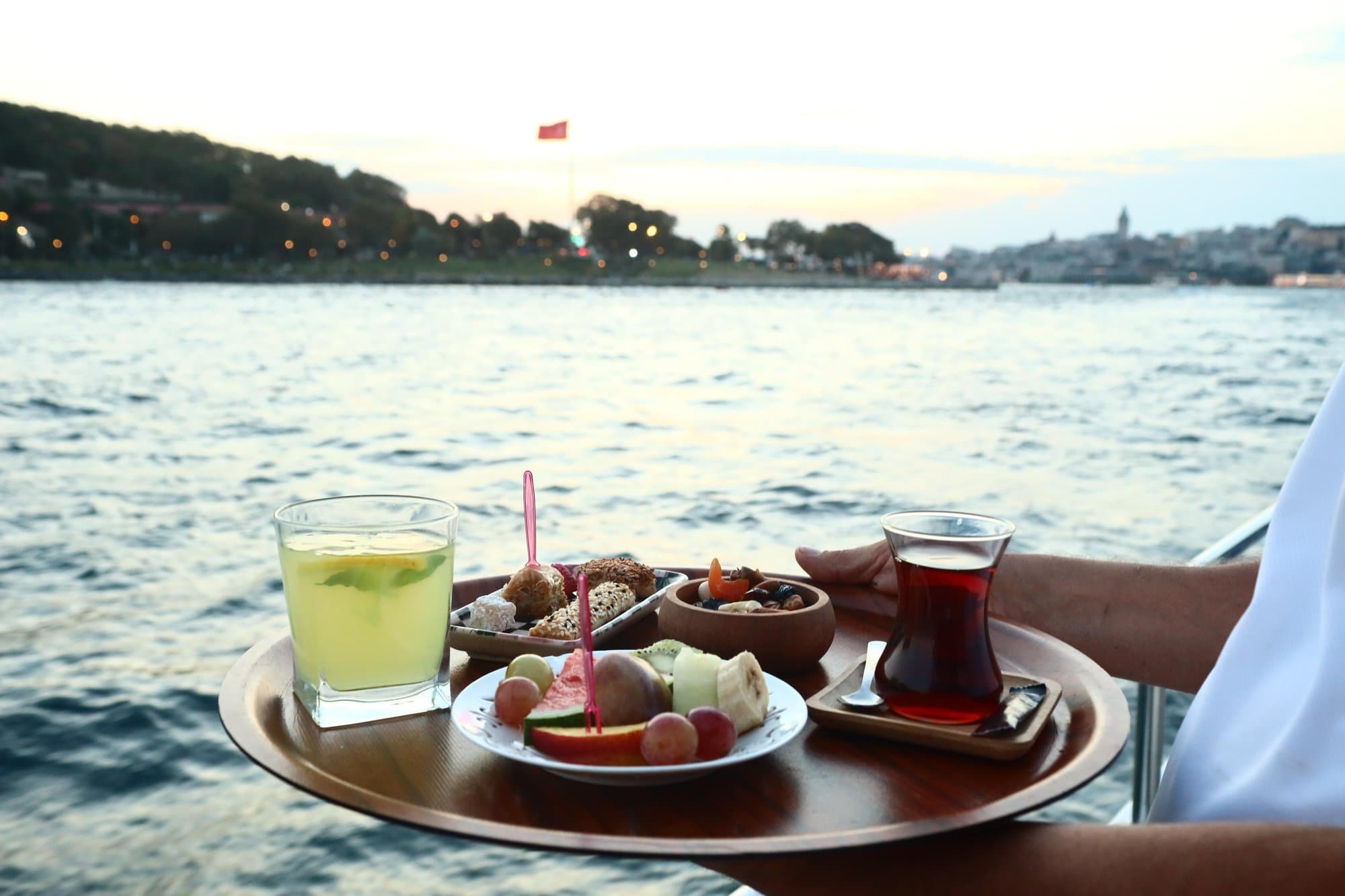 A tray of homemade lemonade, Turkish tea, canapés and a fresh fruit plate over the Bosphorus