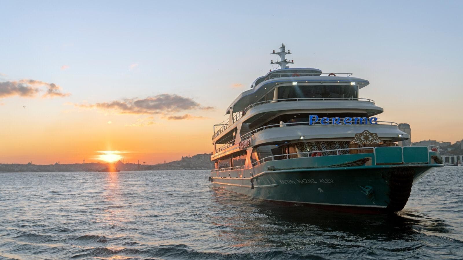 The Pereme Bosphorus tour boat sailing at sunset with the Istanbul skyline behind