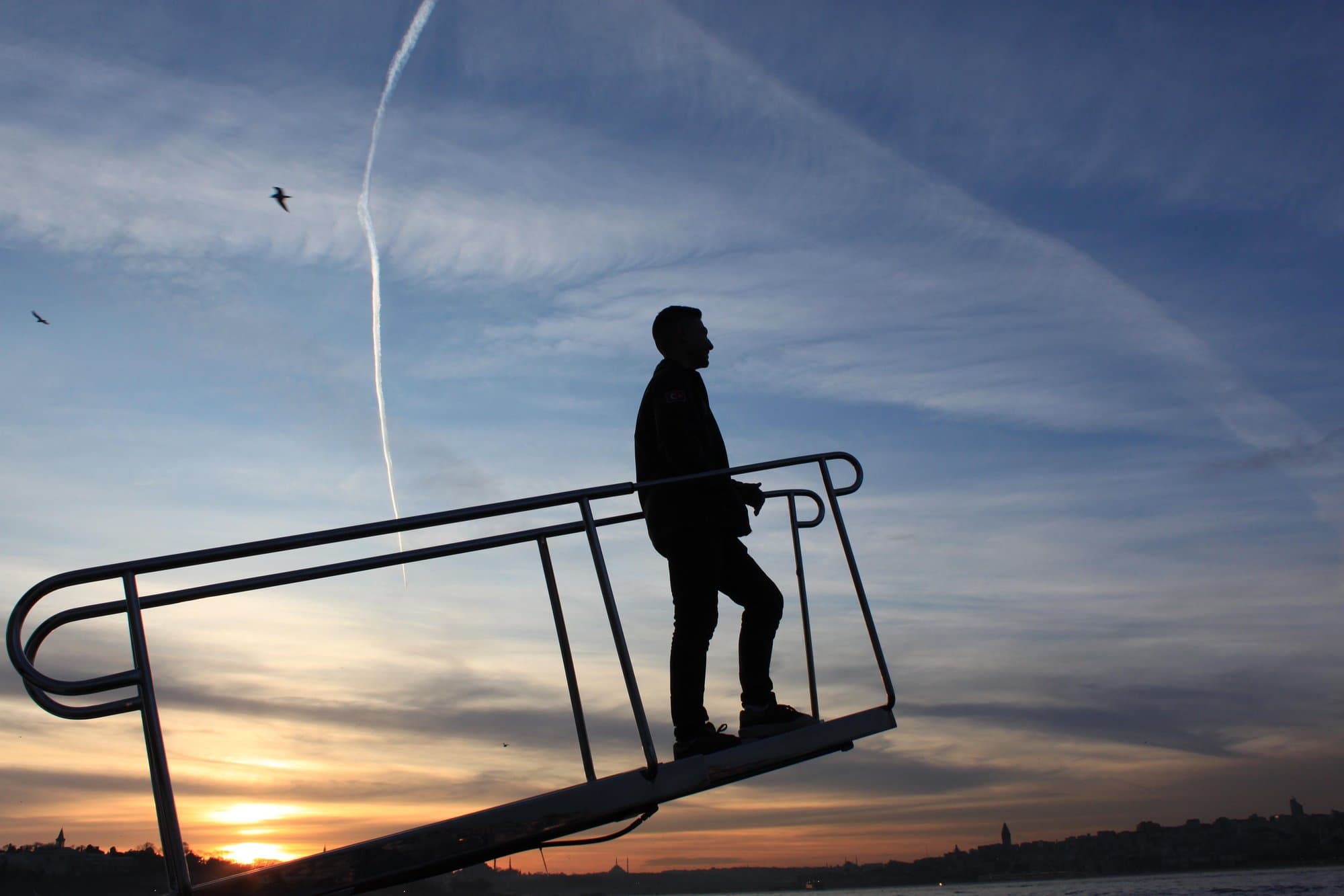 A guest on the boarding ramp at Kabataş with the Istanbul skyline at sunset