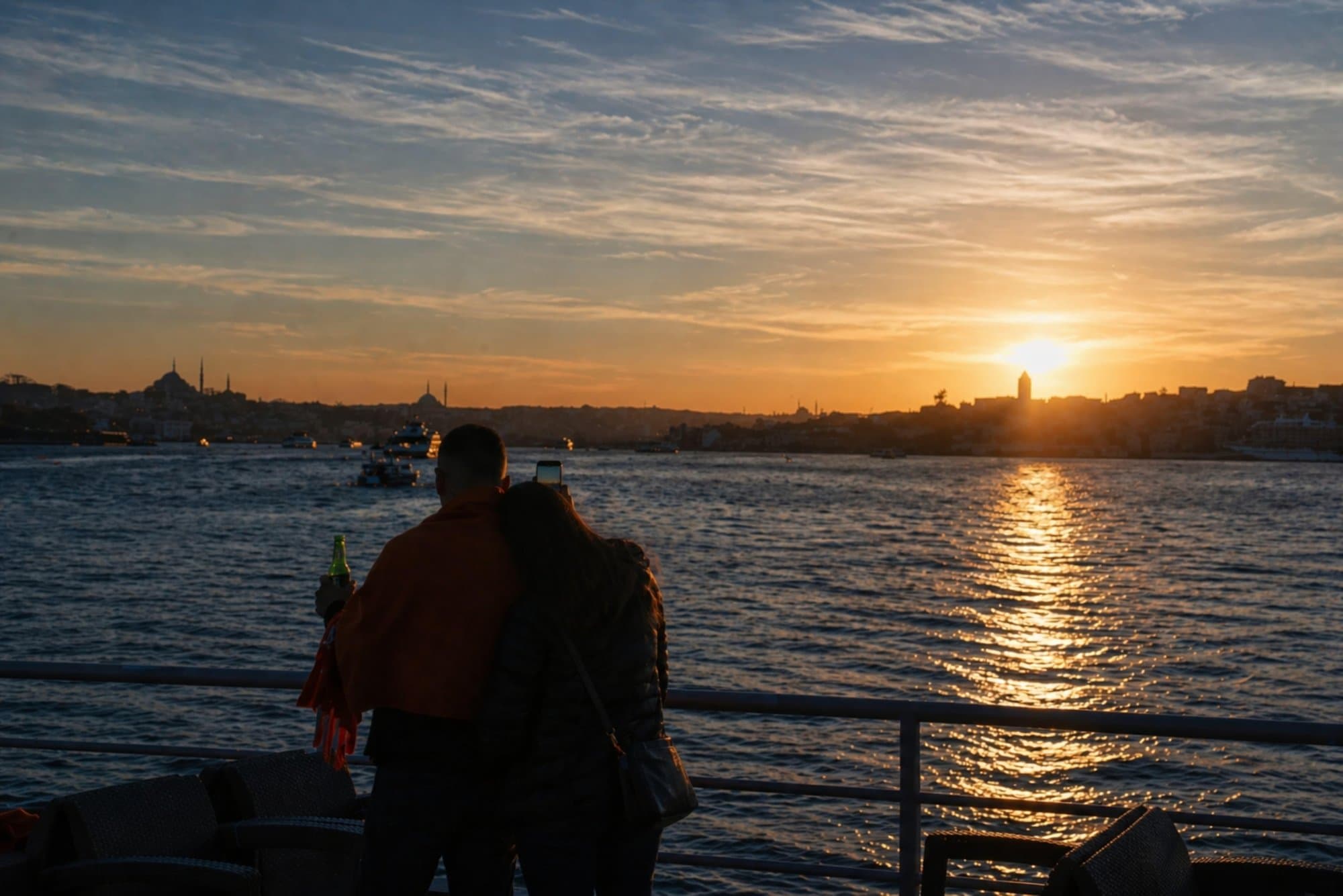 A couple at the deck railing watching the sunset over the Istanbul skyline