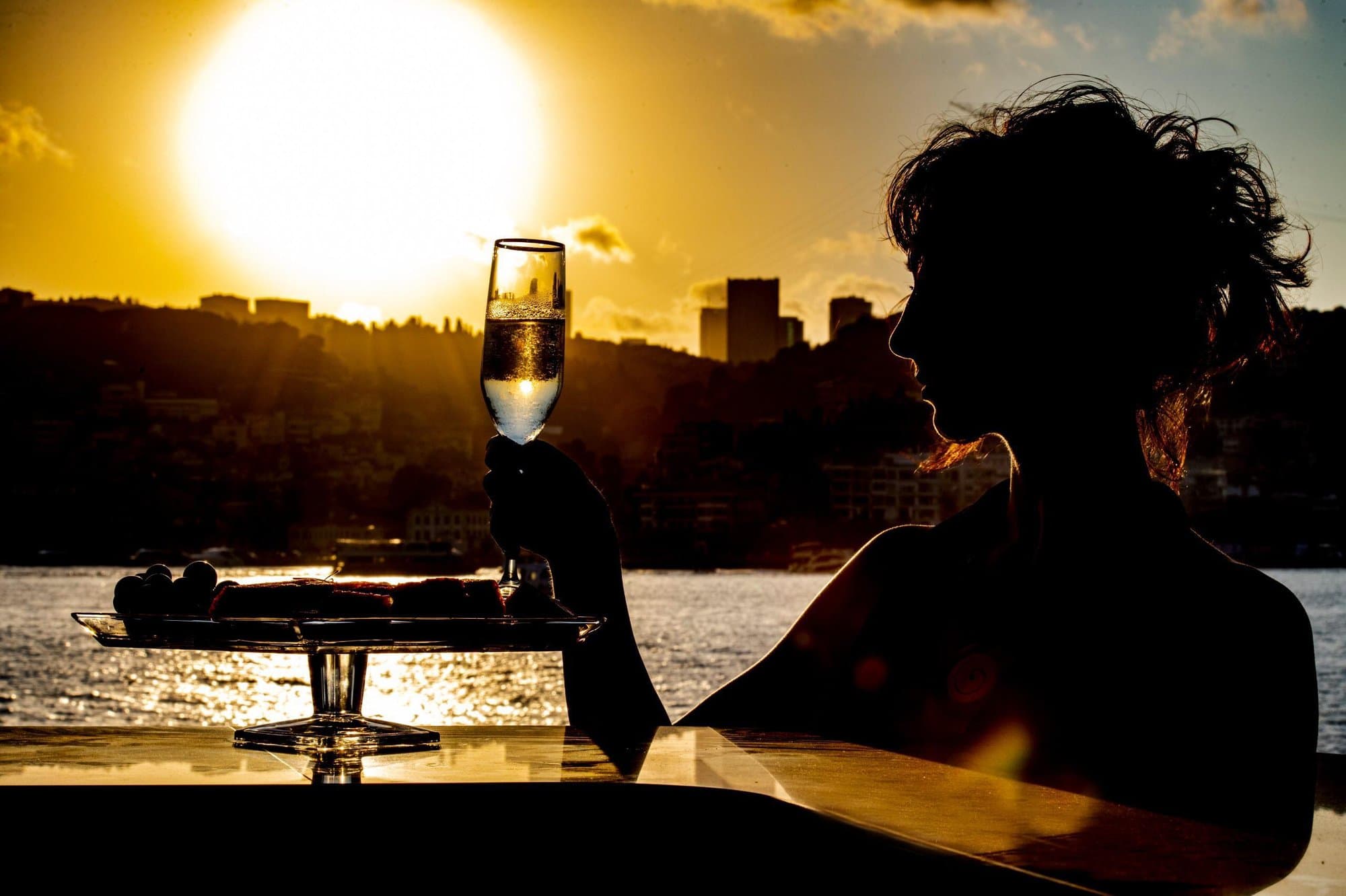 A guest raising a glass in silhouette against the golden Bosphorus sunset