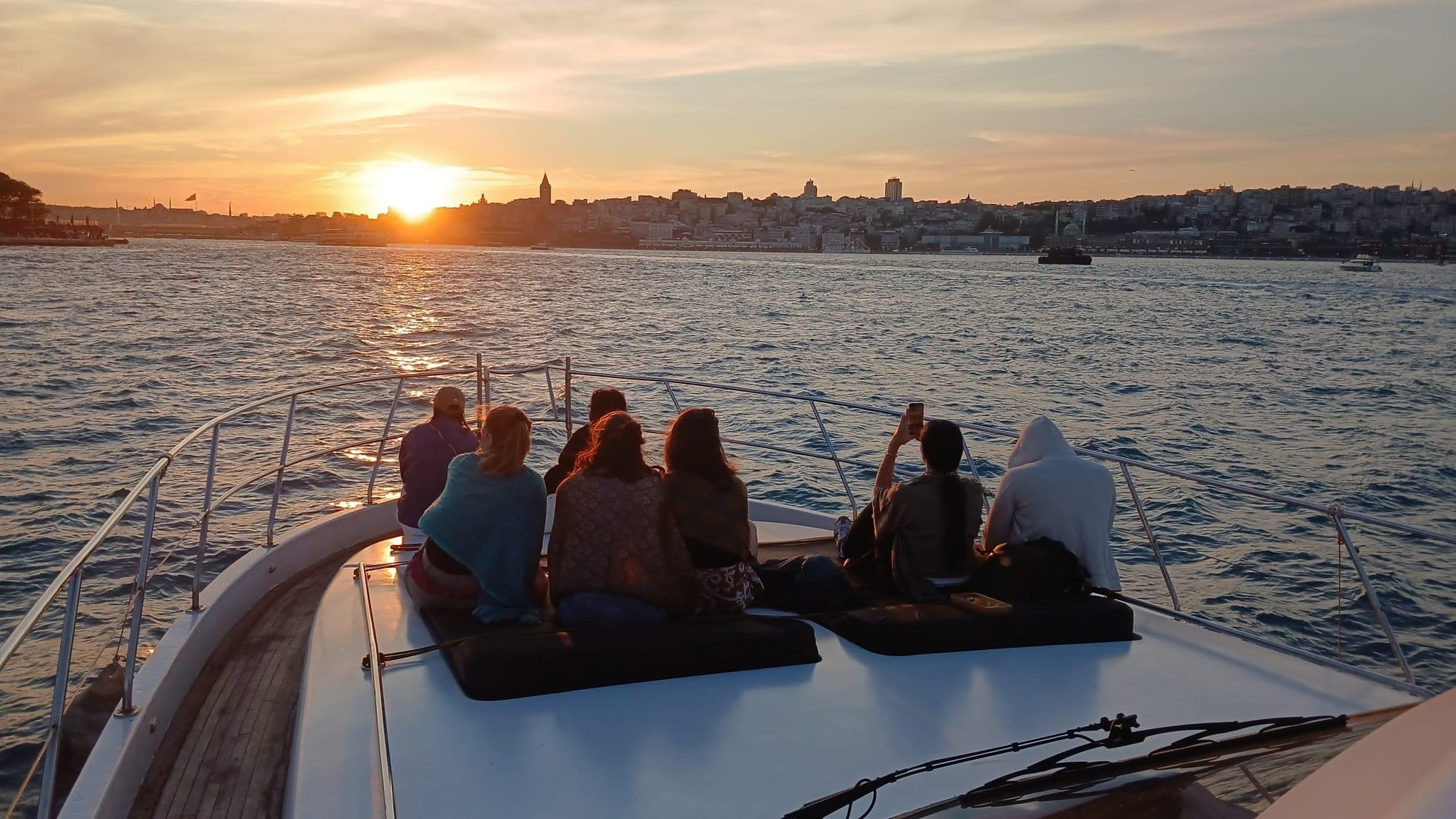 Small group on the yacht bow watching the sunset over the Istanbul skyline