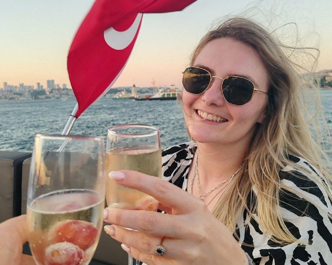 Guests toasting with a glass of wine on deck at sunset