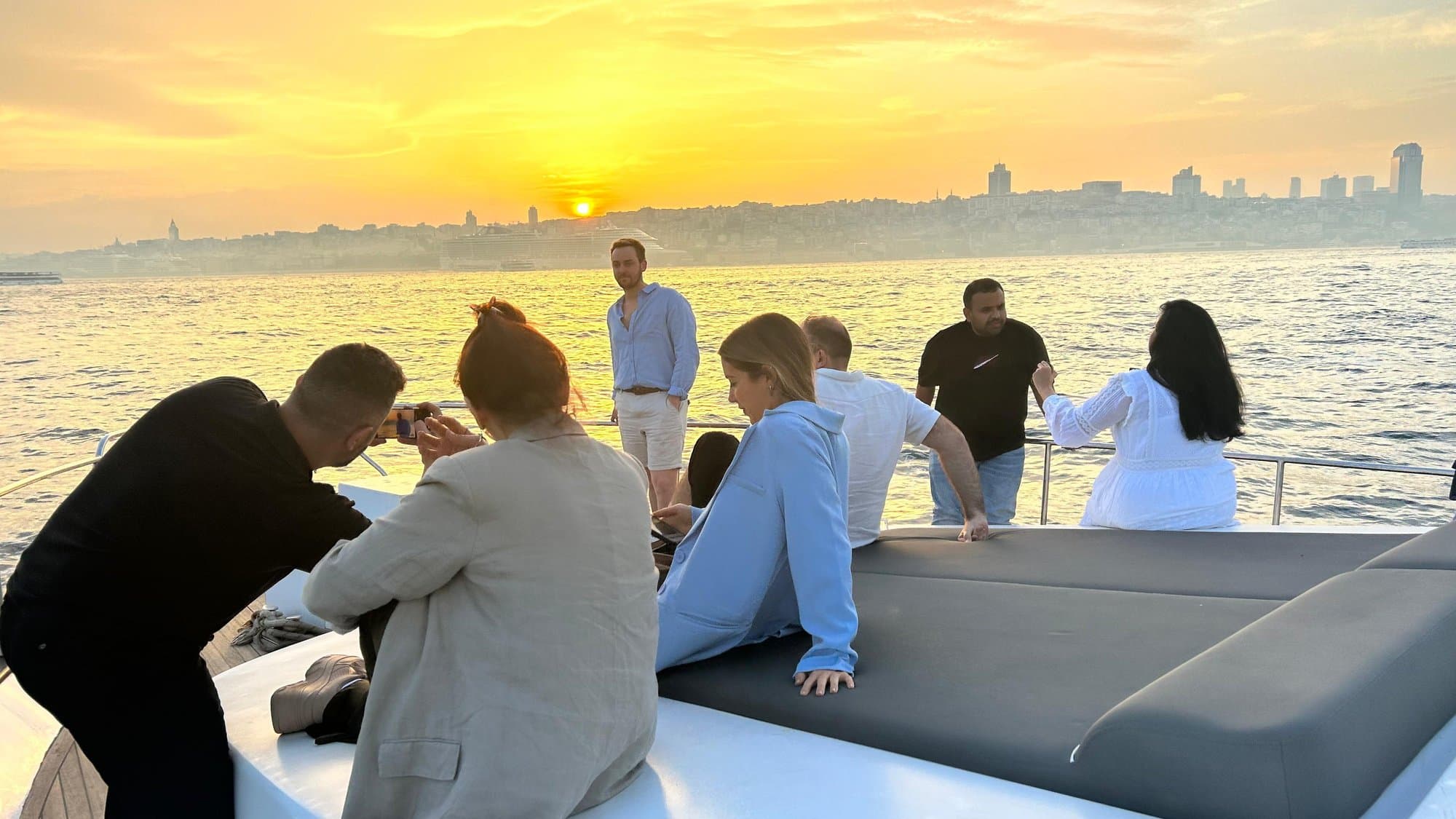 Guests on the yacht's rear deck during golden hour on the Bosphorus