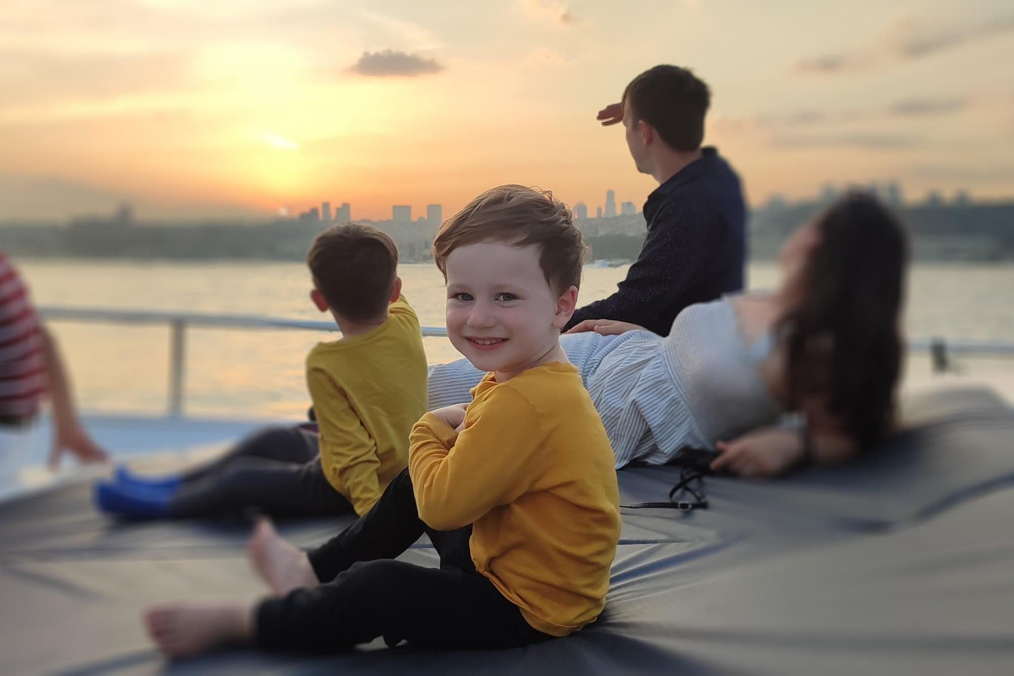A family relaxing on the yacht's deck with the Istanbul skyline behind