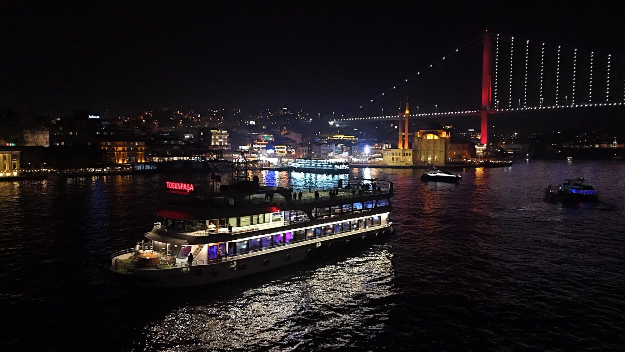 The boat passing the Ortaköy Mosque and the illuminated Bosphorus Bridge at night