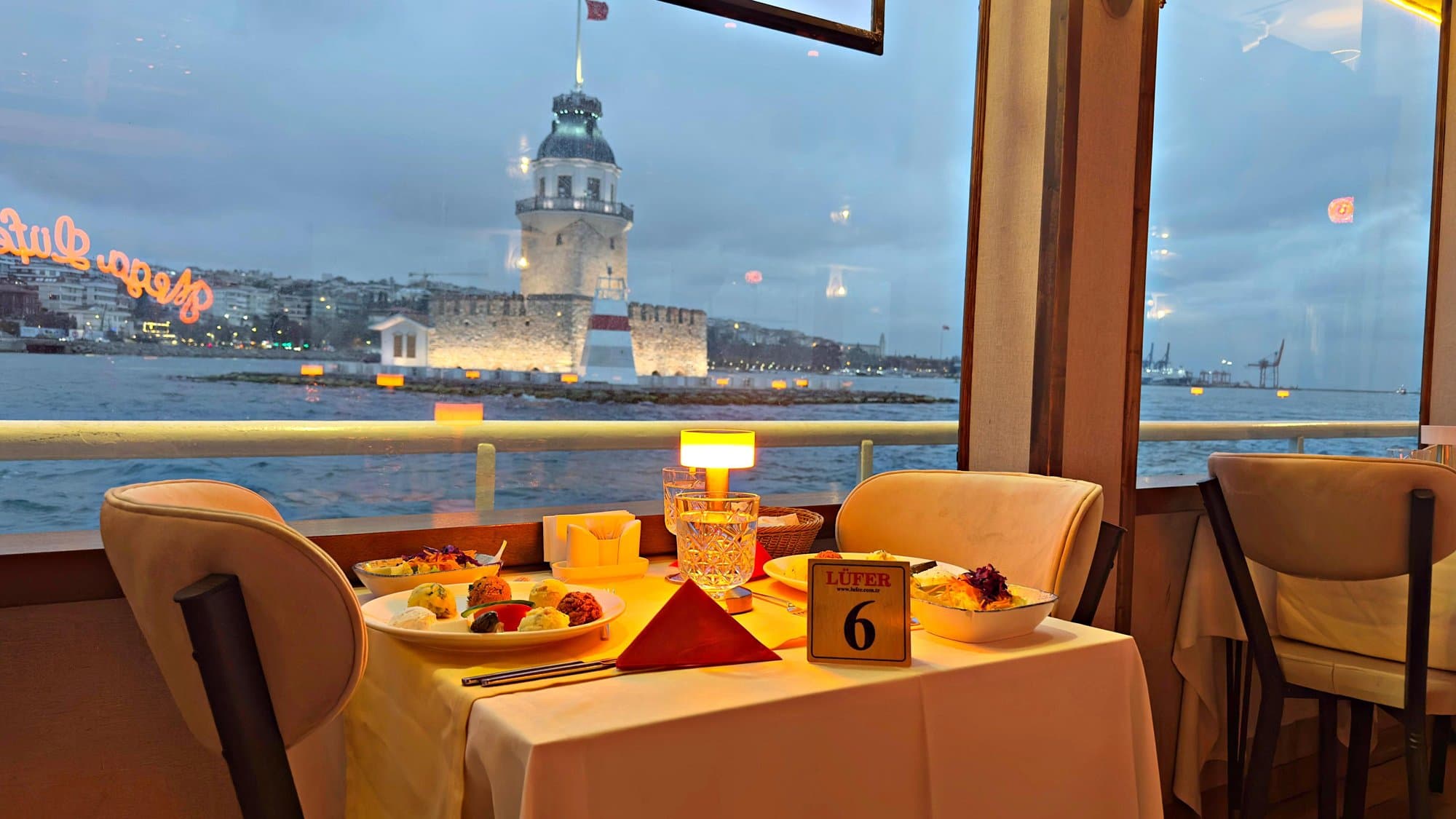 Private window-side table set with Turkish mezes and the Maiden's Tower at dusk