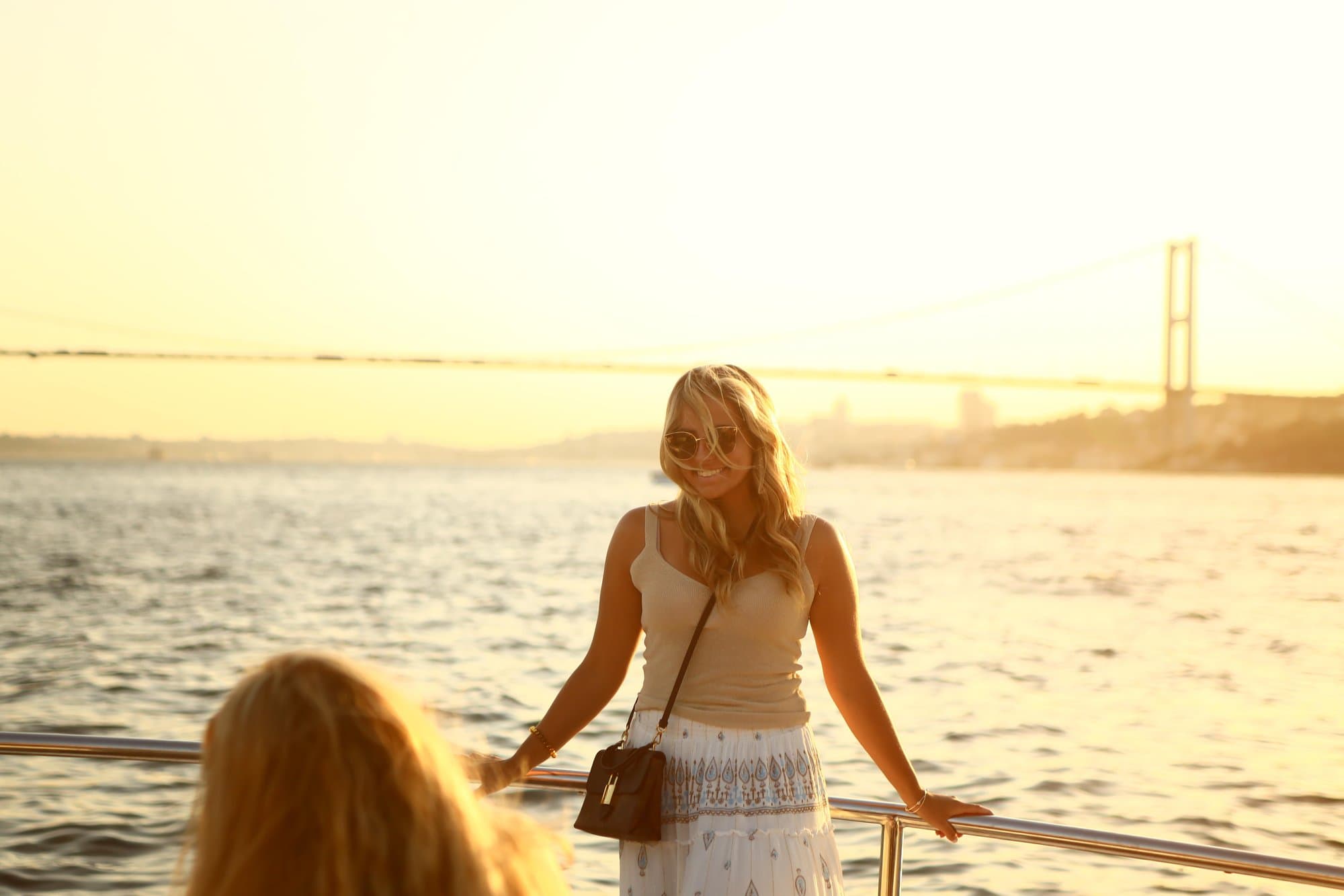 A guest on the yacht's deck with the Bosphorus Bridge in golden evening light