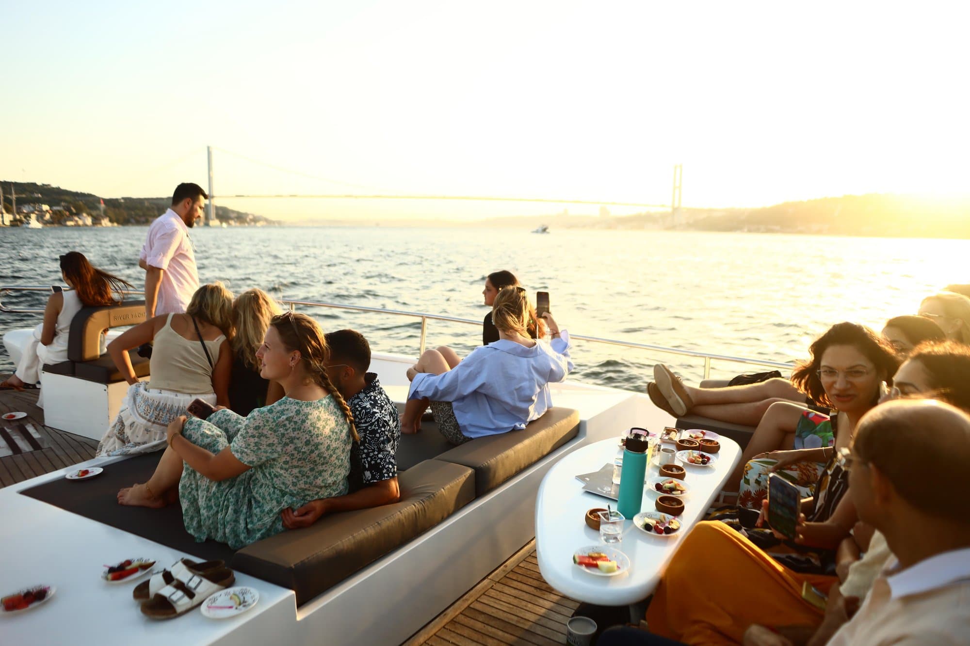 A group relaxing with snacks on the yacht's deck with the Bosphorus Bridge behind